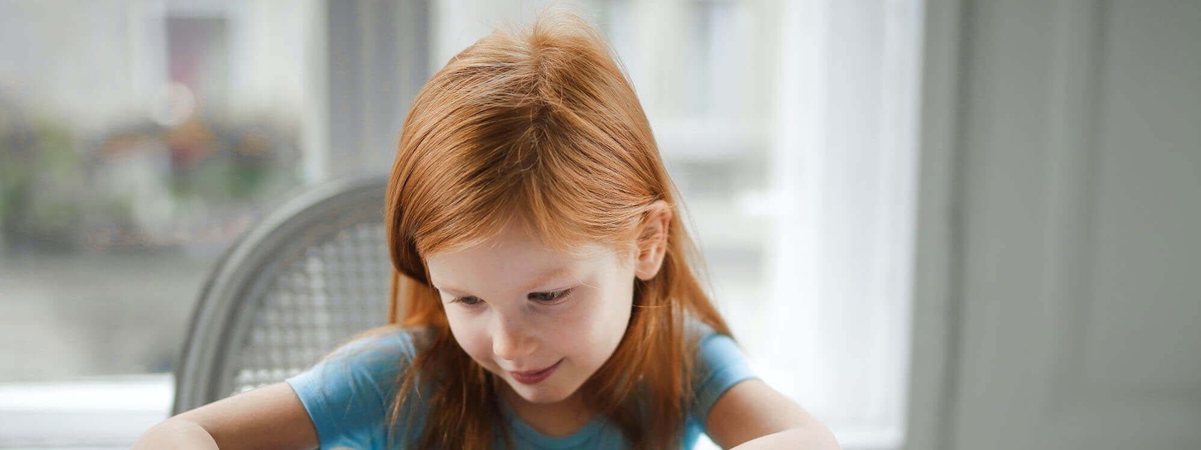 Little red-head girl writing
